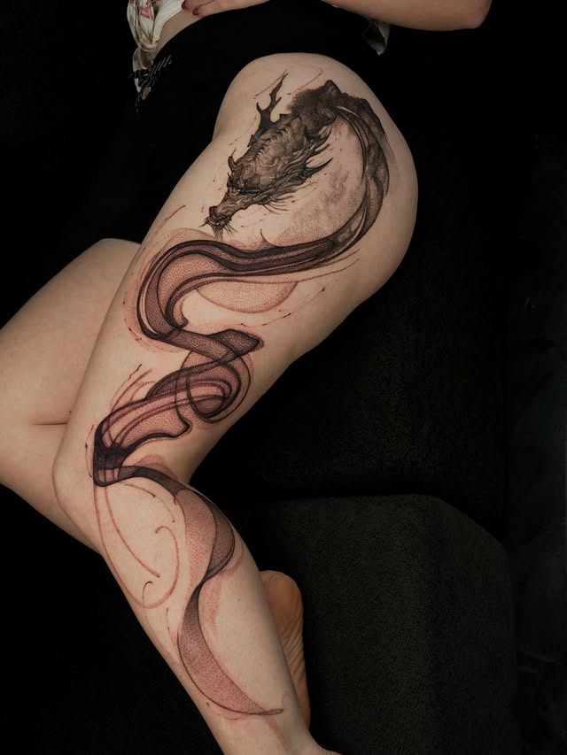 Dragon thigh tattoo with flowing red and black ink